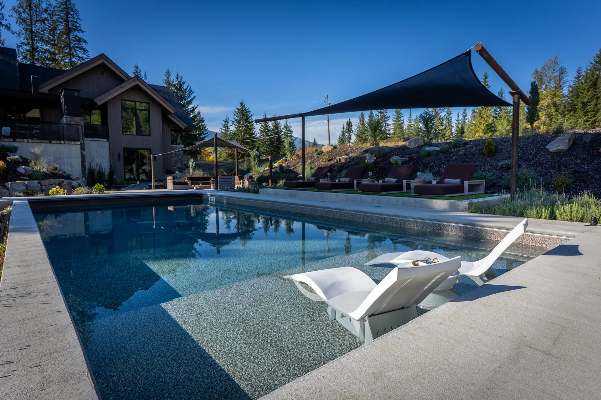 The pool with in-pool loungers, looking back towards the house and shade sail